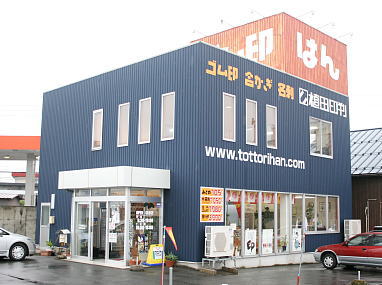 鳥取市の印鑑・はんこ屋【有限会社植田印判 本社】は、青い外観の上に赤地看板が目印です。